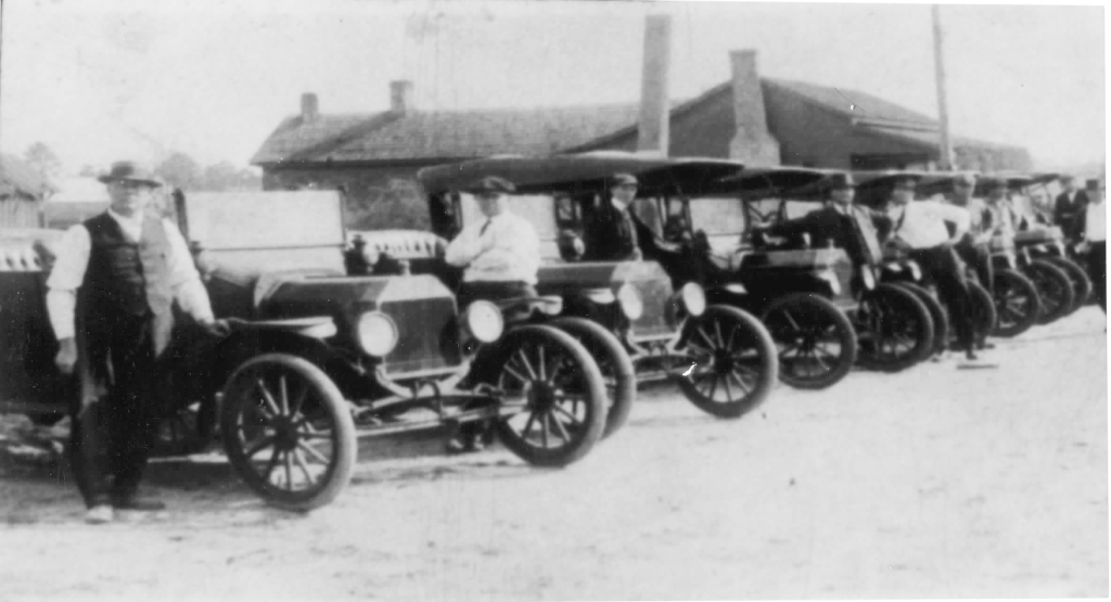 Automobile dealership in Nashville, GA circa 1915 showing men and automobiles on the car lot.